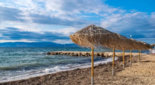 Słomiane parasole na plaży, idealne na relaks. Warto przeczytać angela beach opinie przed podróżą.