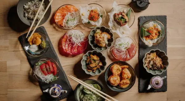Pyszne sushi w Szczecinie czeka! Na stole różnorodne dania: łosoś, tuńczyk, krewetki, ryż i dodatki. Idealne na wspólne jedzenie.