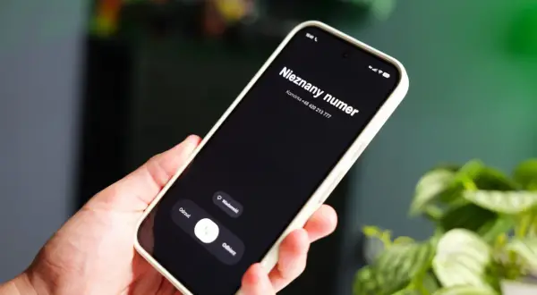 Dłoń trzyma smartfon z ekranem pokazującym "Nieznany numer" i opcje "Odrzuć", "Wiadomość", "Odbierz". Jak sprawdzić czyj to numer?