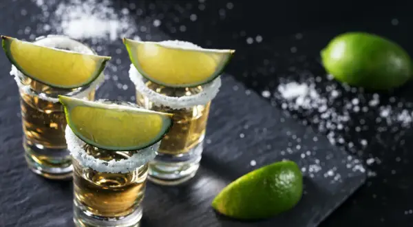Kieliszki tequili z solą i limonką, gotowe do degustacji. Oto jak pić tequilę, by poczuć pełnię smaku.