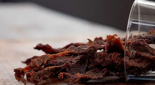 Leckeres beef jerky selber machen ist gar nicht schwer! Hier ist ein Haufen selbstgemachtes Beef Jerky, das aus einem Glas gekippt wurde.