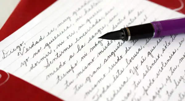 A purple fountain pen rests on a letter written in elegant cursive, demonstrating how to write it in cursive.