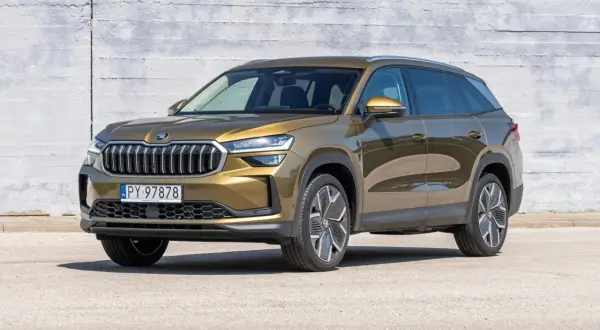 Złoty Skoda Kodiaq stoi przed betonową ścianą. Poznaj jego imponujące skoda kodiaq wymiary, idealne na rodzinne podróże.