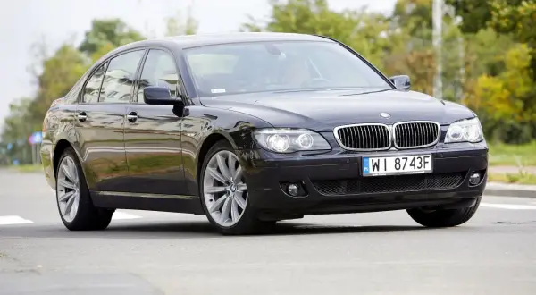 Eleganckie czarne BMW 730d na polskich tablicach WI 8743F jedzie po drodze, otoczone zielenią.