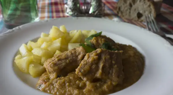 Sabrosa carne guisada con verduras y patatas, servida en un plato blanco.