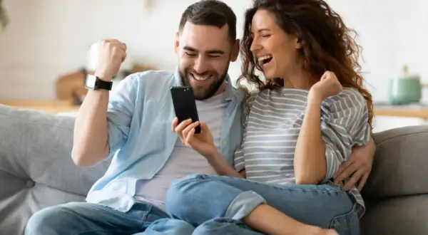 Para jak z liceum, zakochani, cieszą się z sukcesu, patrząc na telefon.