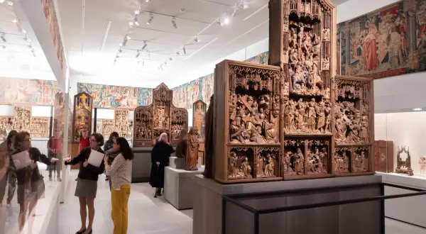 Besucher bestaunen im Cluny Museum detailreiche Holzschnitzereien und Wandteppiche.