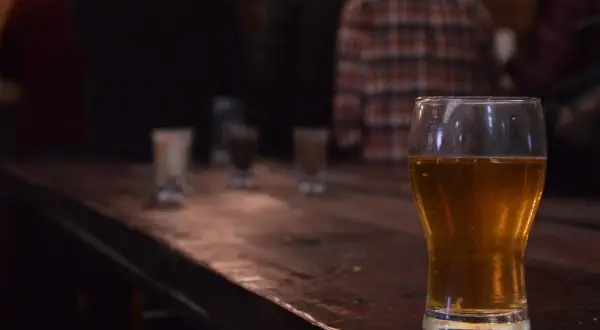 Zimne IPA na drewnianym blacie, w tle ludzie. Idealne na wieczór.