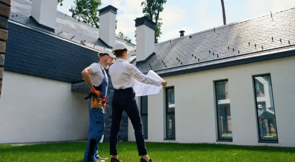 Architekt i budowlaniec omawiają plany domu. Czy można mieszkać w domu bez odbioru? To pytanie, na które odpowiedź znajdą na tym etapie budowy.