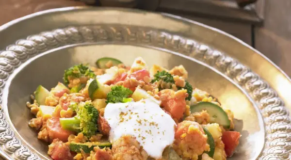 Herzhaftes Linsengericht mit Brokkoli, Zucchini und Tomaten, garniert mit einem Klecks Joghurt. Ein köstliches Beispiel für Linsen Rezepte.