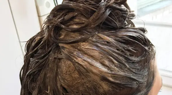 Dunkelbraunes Haar mit Farbauftrag, das auf die Einwirkzeit wartet. Wie lange muss Farbe beim Friseur einwirken?