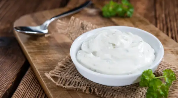 Cremige Sour Cream in einer Schale, bereit zum Dippen. Ein Löffel liegt daneben.