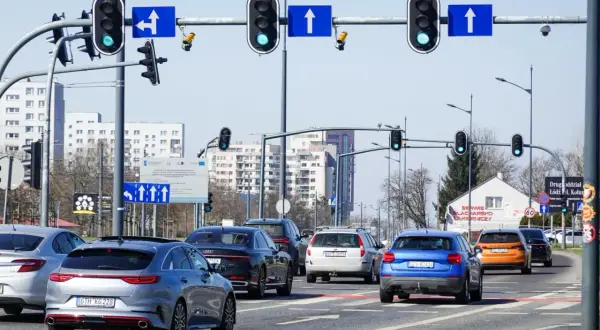 Na skrzyżowaniu z sygnalizacją świetlną, gdzie są kamery rejestrujące przejazd na czerwonym świetle, stoi kilka samochodów.