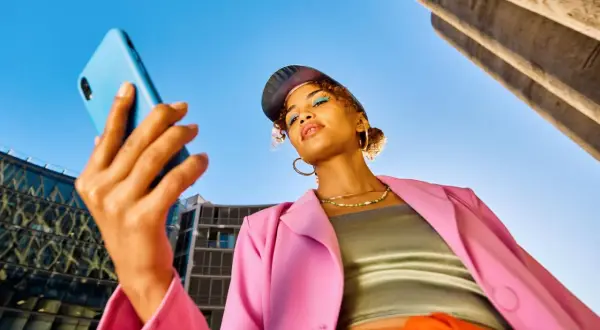Junge Frau mit Handy in der Hand, blickt nachdenklich. Ist Influencer ein Beruf? Sie inspiriert mit ihrem Style.