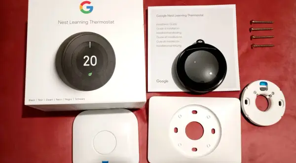 Kit pour l'installation d'un thermostat Nest Learning. Boîte, manuel, thermostat, socle et vis.