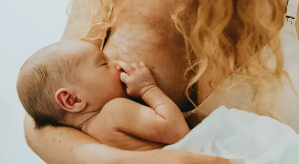 En bebis ammas, med handen vid munnen. En lugn stund för mamma var tredje timme.
