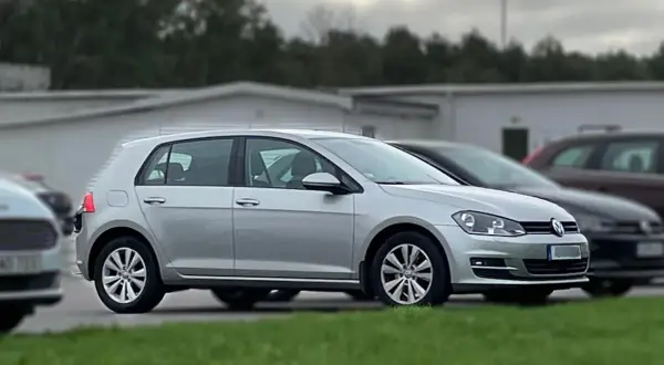 Silver tsi golf parkerad på en gräsmatta framför en vit byggnad.