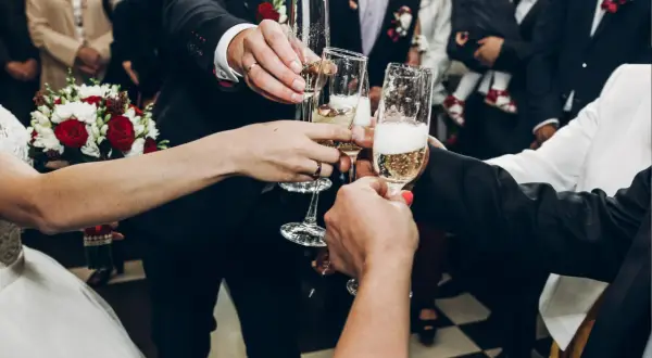 Para wznosi toast kieliszkami szampana. Zastanawiasz się, ile wódki na wesele? To zdjęcie nie odpowie, ale pokazuje radość!