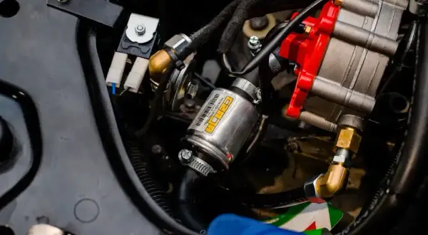 Uszkodzony map sensor lpg objawy: metalowy element z żółtą etykietą, przewody i czerwona część regulatora.