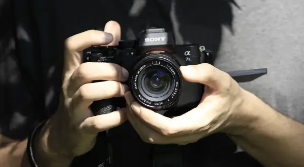 Dłonie trzymające aparat Sony Alpha 7s, gotowe do ustawienia ostrości.