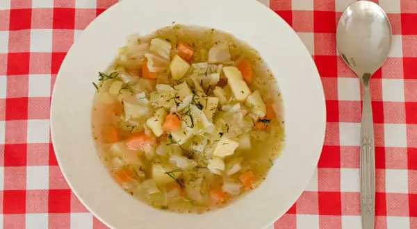 Aromaticzna zupa ze słodkiej kapusty z ziemniakami i marchewką, posypana świeżym koperkiem.