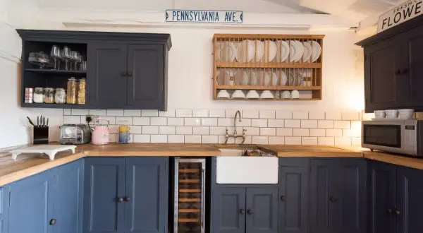 Cocina renovada sin obras: armarios azul marino, encimera de madera, fregadero blanco y suelo de baldosas a cuadros.