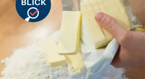 Verbraucherblick: Welche Butter ist die beste? Ein Messer schneidet Butter, die auf Mehl liegt.