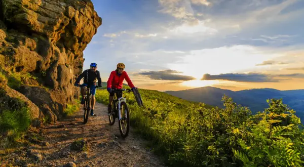 Dwóch rowerzystów na szlaku górskim podczas zachodu słońca. To idealny przykład turystyki rowerowej w Polsce.