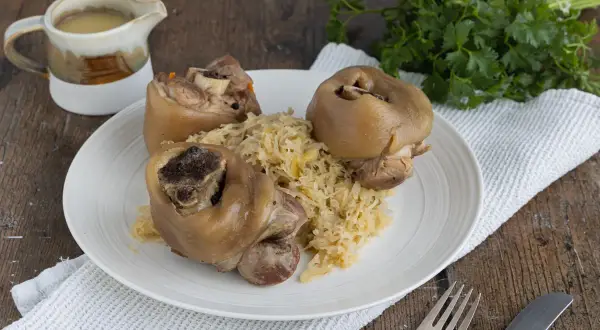 Drei deftige Eisbeine auf Sauerkraut, serviert mit Soße. Ein klassisches Eisbein Rezept für Genießer.