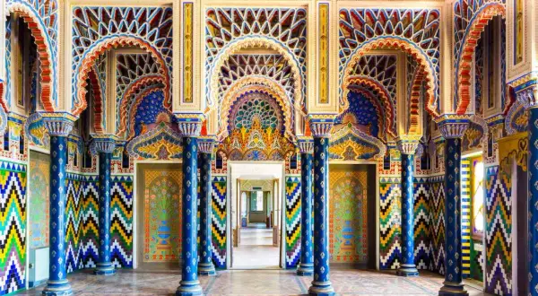 Intérieur du Castello di Sammezzano, une salle aux arcs mauresques, colonnes bleues et motifs géométriques colorés.