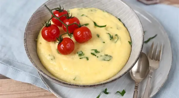 Cremige Polenta, ein italienisches Rezept, garniert mit Kirschtomaten und Petersilie.