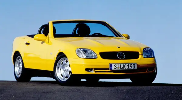 Żółty kabriolet Mercedes SLK na tle błękitnego nieba.