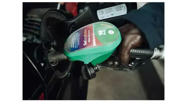 En hand med brun handske håller i en bensinpump med etiketten "GoEasyExtra 98 Bensin E5".