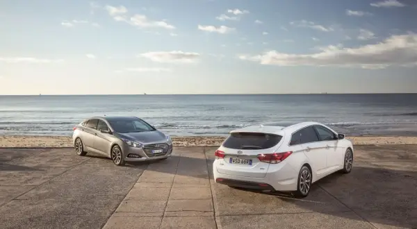 Dwa Hyundai i40, sedan i kombi, stoją nad brzegiem morza. Wiele pozytywnych hyundai i40 opinie potwierdza ich wszechstronność.