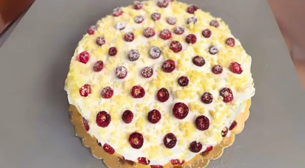 Torta pan di spagna decorata con panna, fragoline di bosco e briciole di pan di spagna. Un dolce invitante e colorato.