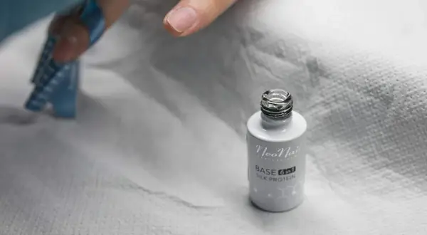 Czy baza proteinowa niszczy paznokcie? Na zdjęciu buteleczka bazy NeoNail Silk Protein i przygotowywany paznokieć do stylizacji.