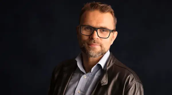 Jacek Bartosiak w skórzanej kurtce i okularach, autor inspirujących książek.