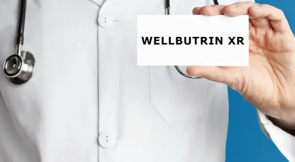Lekarz w białym kitlu prezentuje kartkę z napisem WELLBUTRIN XR.