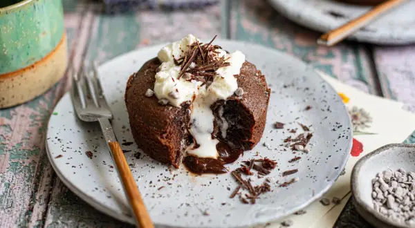 Ein Schokoladen-Lava-Kuchen mit flüssigem Kern, garniert mit Schlagsahne und Schokostreuseln. Ein perfektes Lava cake rezept für Genießer.