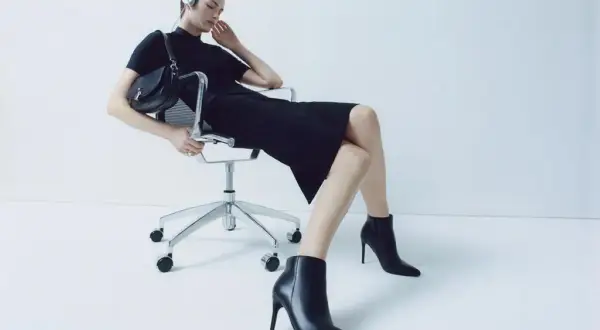 Eleganckie stylizacje z botkami na obcasie. Kobieta w czarnej sukience i botkach na szpilce, słuchająca muzyki.