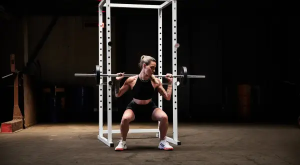 Kvinna utför squats med stång i ett gym.