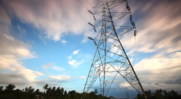 Wieża energetyczna na tle nieba z chmurami. Linie energetyczne, jak taryfa G13, łączą krajobraz.