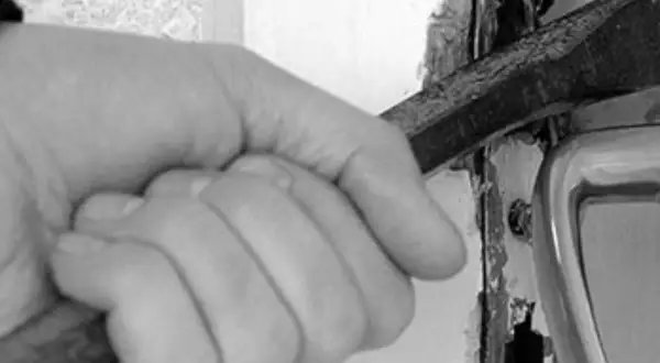 Mano con cincel forzando una puerta, una imagen que evoca la problemática de los okupas en España.