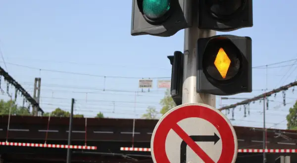 Feux orange clignotant sur un passage à niveau. Le panneau "interdit de tourner à droite" est visible.