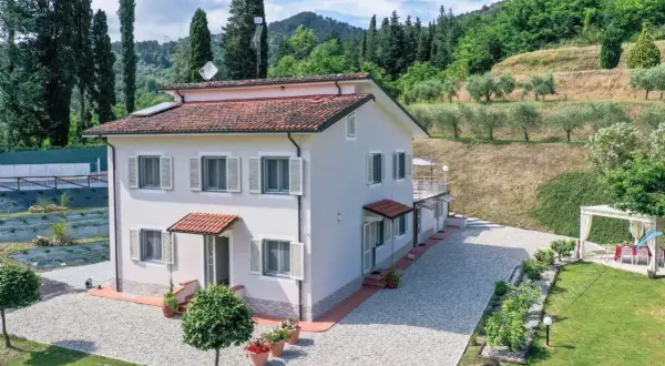 Villa unifamiliare immersa nel verde, con un ampio giardino, uliveto e vista collinare.