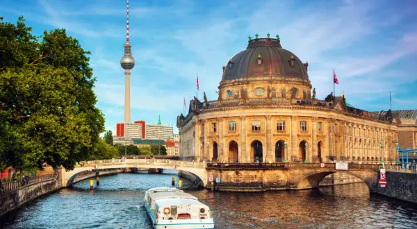En båt på Spree-floden framför Bode-museet och Fernsehturm. En perfekt vy för din berlin reseguide.