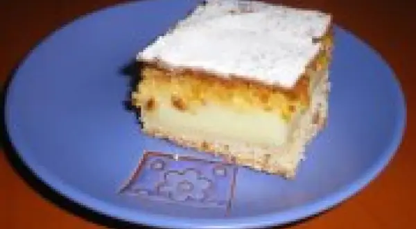 Pyszna kremówka kokosowa na niebieskim talerzyku, posypana cukrem pudrem.