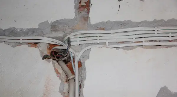 Nowe kable elektryczne w ścianie, przygotowanie do wymiany instalacji elektrycznej. Widoczne przewody i puszka instalacyjna.