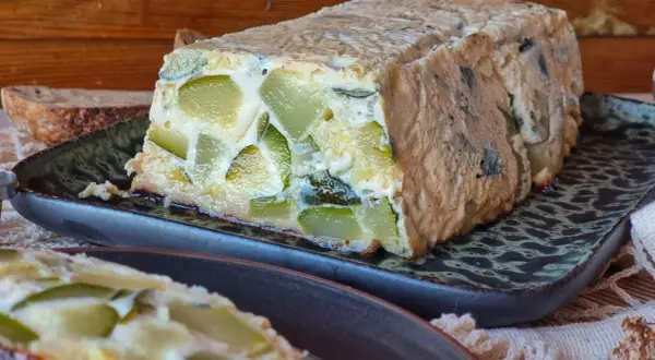 Pastel de calabacín casero, con trozos verdes visibles en una masa dorada, servido en plato oscuro.