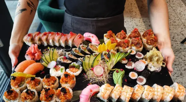 Ogromna taca z różnorodnym jedzeniem sushi: rolki z łososiem, tuńczykiem, krewetkami, a także nigiri i sashimi.